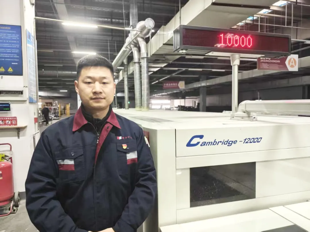 Liu Zhaoyang standing next to Cambridge-12000 Perfect Binding Line at JMD printing factory